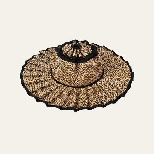 Woven straw hat with black trim on a beige background foldable pleated and waterproof