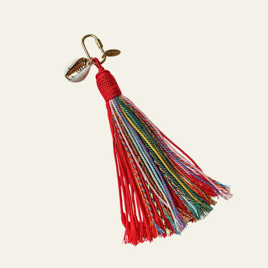 Colorful tassel keychain on a beige background bag charm with gold shell detail